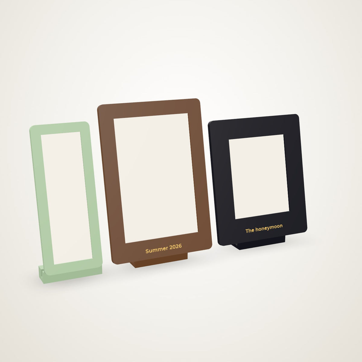 Three slide-in photo frames on their feet - a photo-booth strip in sage, a 4 x 6 in walnut with a gold caption, a Polaroid in black